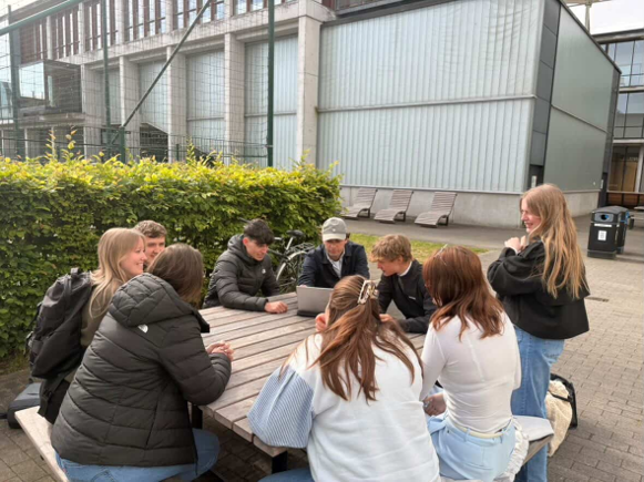 De TagMate-focusgroep zittend rond een tafel op de campus, met een laptop in het midden